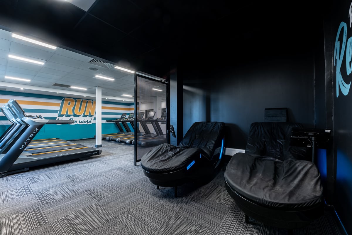 PureGym London Muswell Hill: Rows of treadmills, sleek black reclined exercise machines, mirrored walls in dimly lit studio.