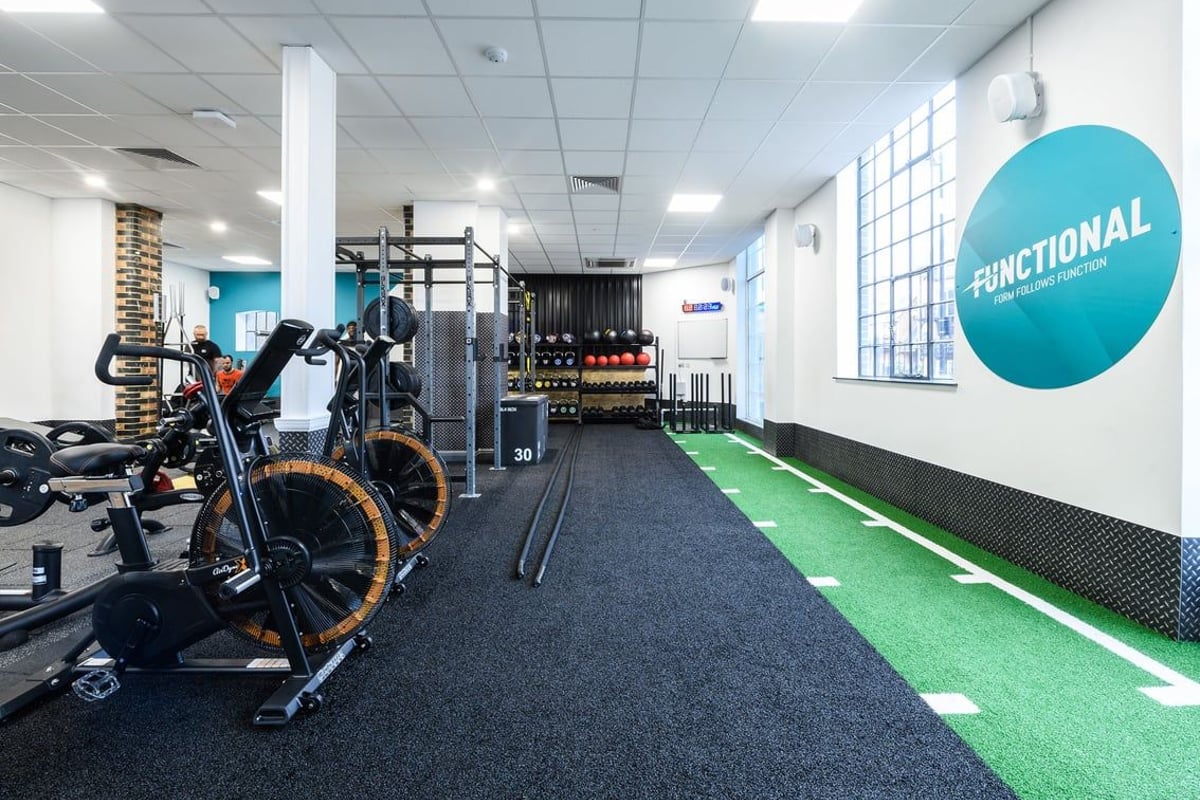 PureGym London Bow Wharf: Functional training area with sled, battle ropes, turf, weight plates, squat racks.