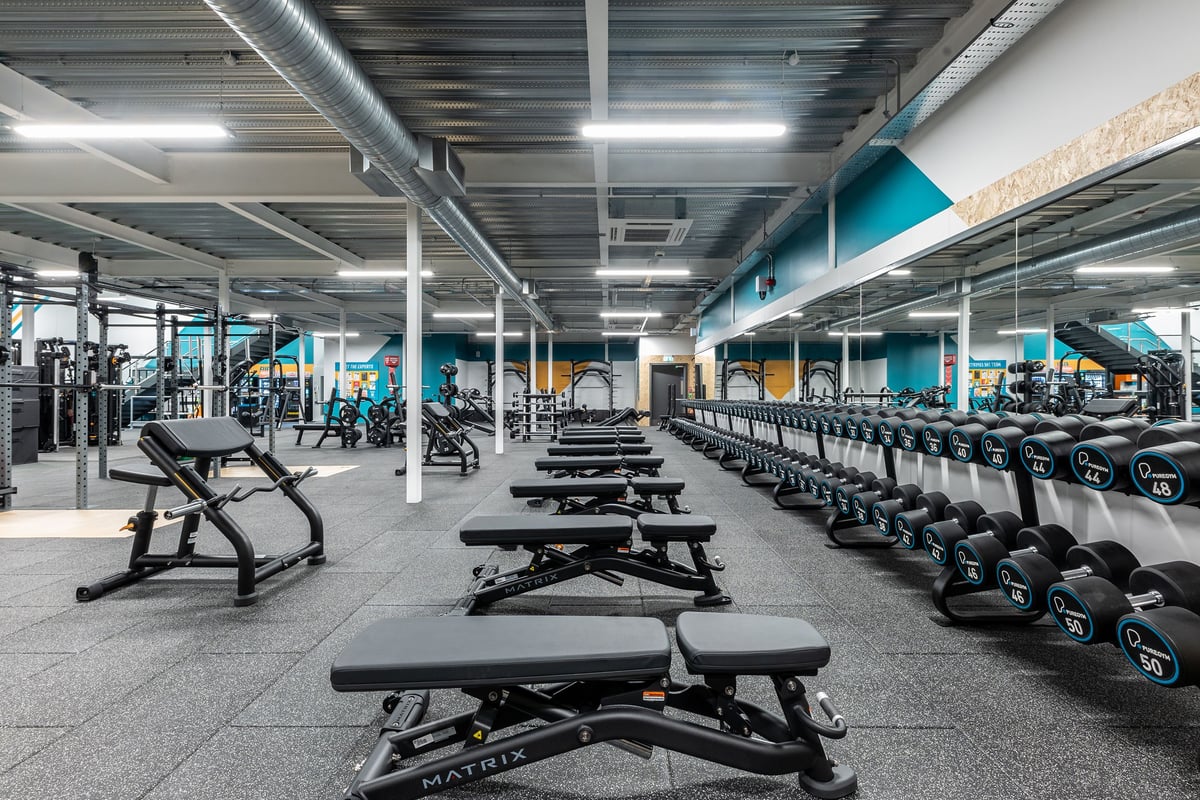 PureGym Eastbourne: Rows of weight benches, dumbbells, and exercise equipment in a spacious gym interior.