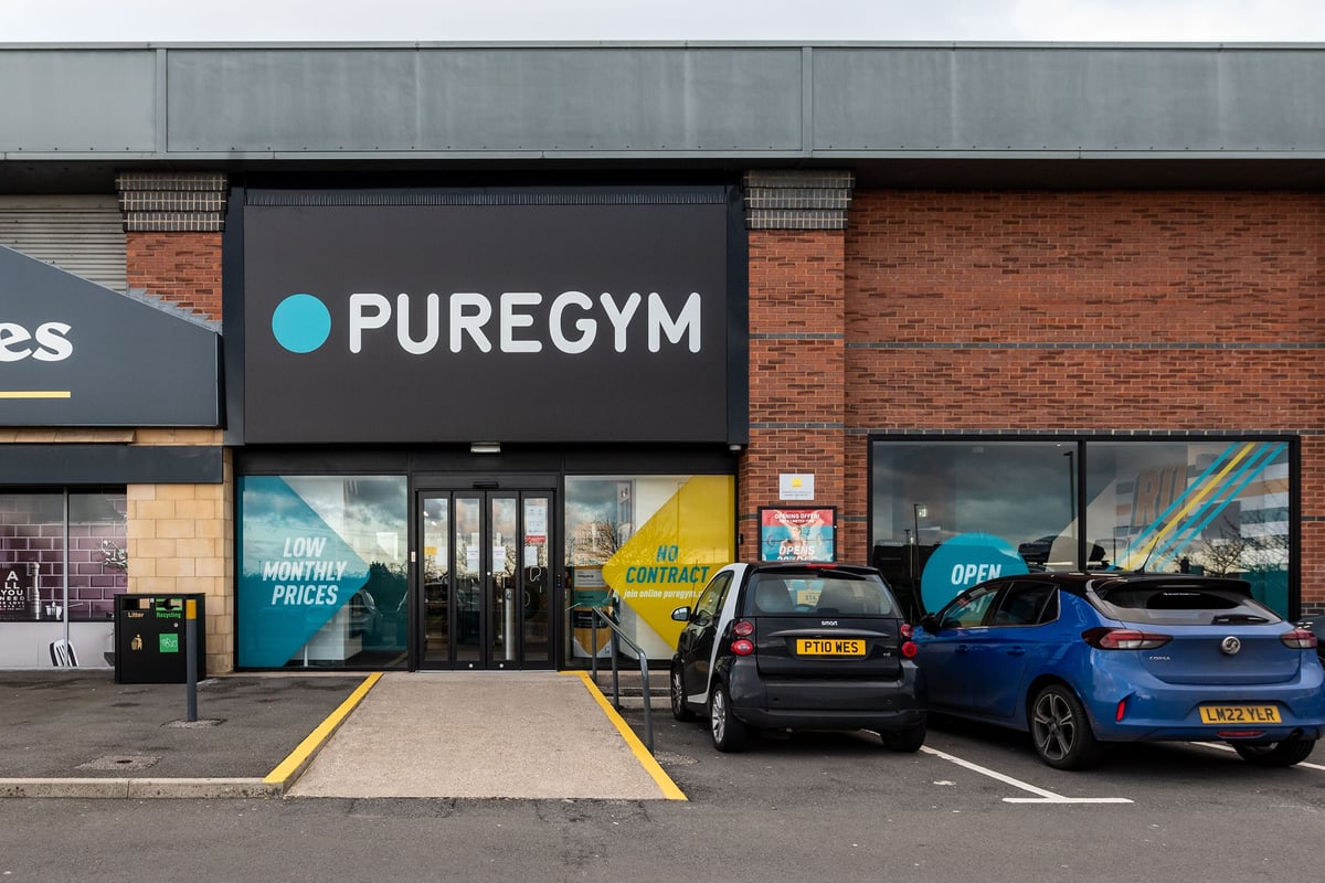 PureGym Letchworth: The gym building exterior with signage, parking spaces, and vehicles.