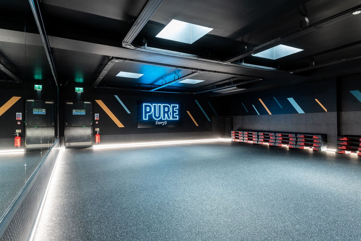 PureGym London Bayswater: Pure-branded treadmills, benches along mirrored walls in a futuristic studio interior
