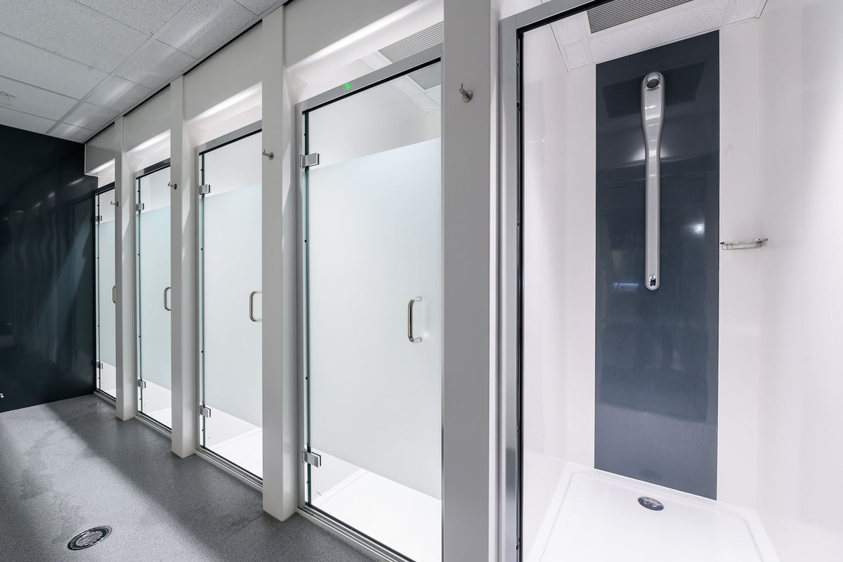 PureGym London Fulham: Glass-enclosed shower stalls in a locker room or changing facility.
