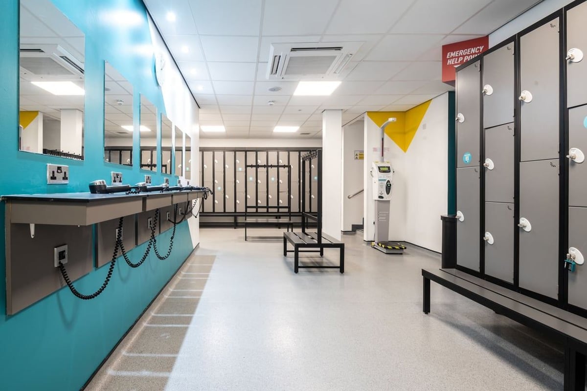 PureGym Dunfermline: Lockers, benches, sinks along blue-tiled wall, typical changing room interior.