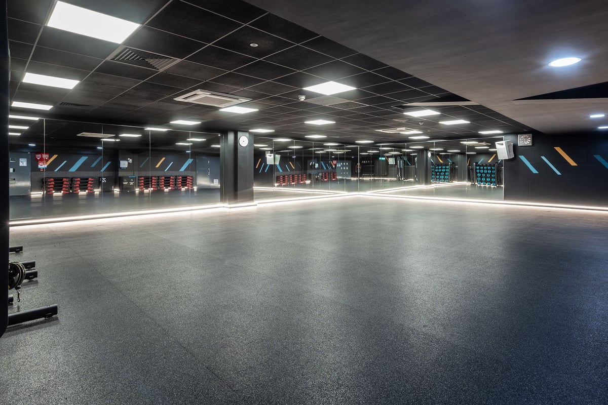 PureGym Sutton Coldfield: Rows of resistance machines, benches, mirrored walls, and rubberised flooring in a gym setting.