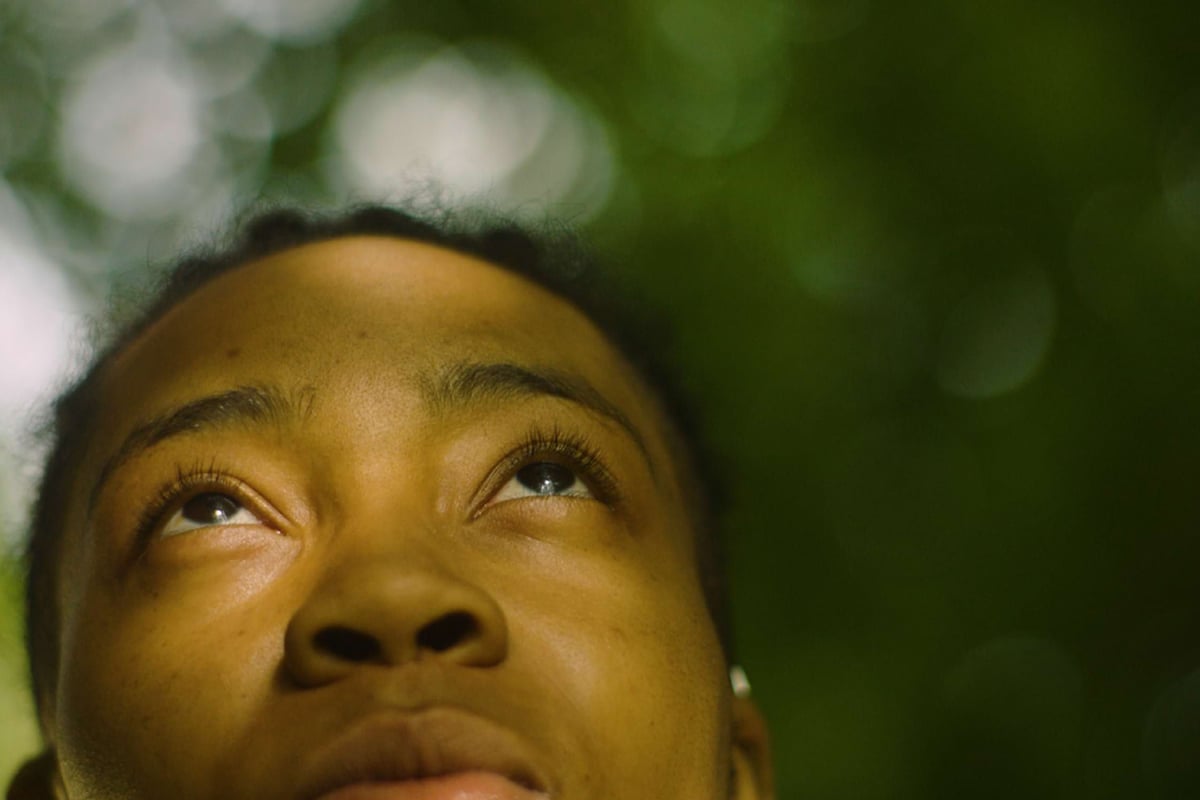 Close-up of a person looking upwards with a blurred green background