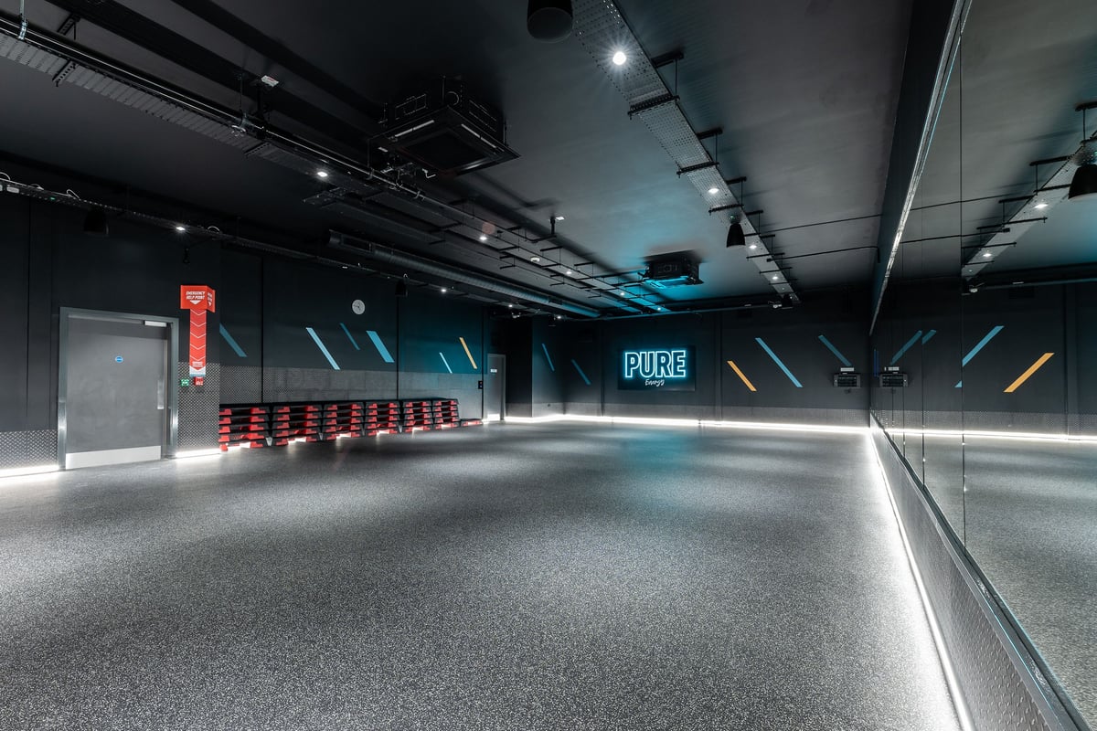 PureGym Sheffield Meadowhall Retail Park: Red bench seating, grey rubberized floor, with "PURE" signage in bluish lighting.