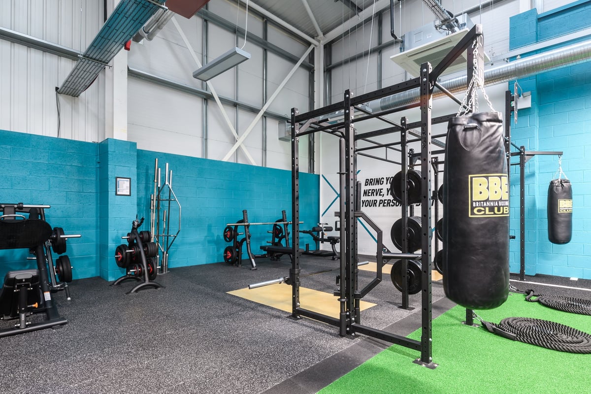 PureGym Buckingham: Functional training rig, punching bags, rubberized flooring, weight racks, and turf area.