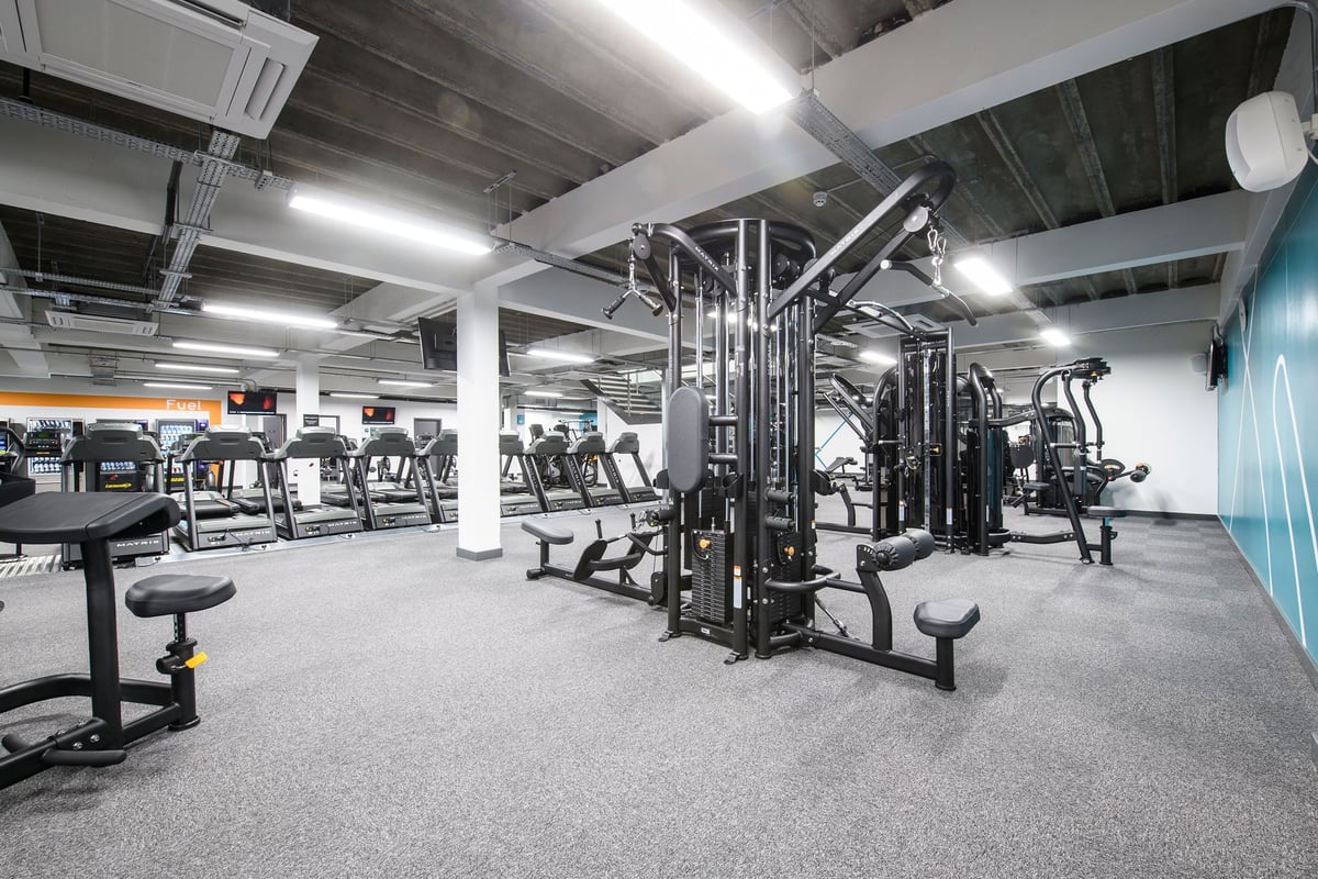 PureGym Brighton London Road: Strength training area with cable machines, weight racks, benches, and rubberized flooring.