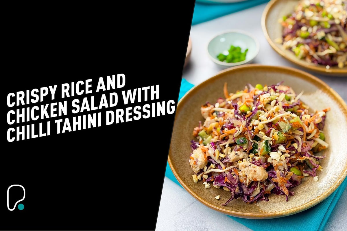 Two plates of colourful crispy rice and chicken salad with chopped vegetables and nuts