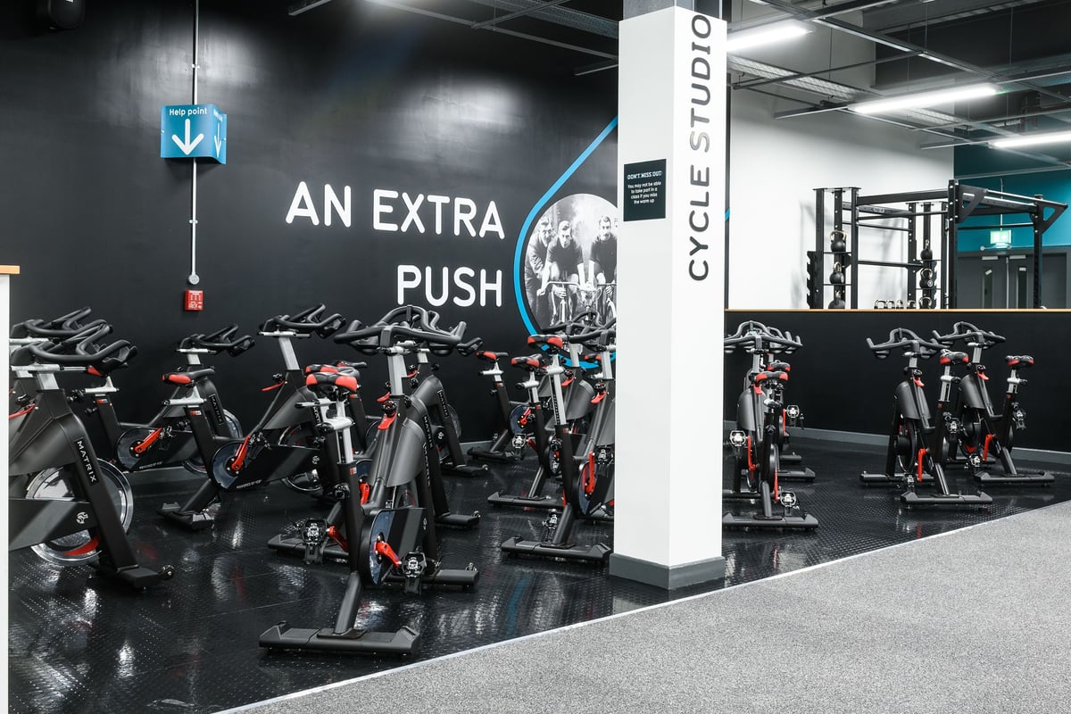 PureGym Newry: Rows of stationary bikes, motivational signage, and cycle studio branding.