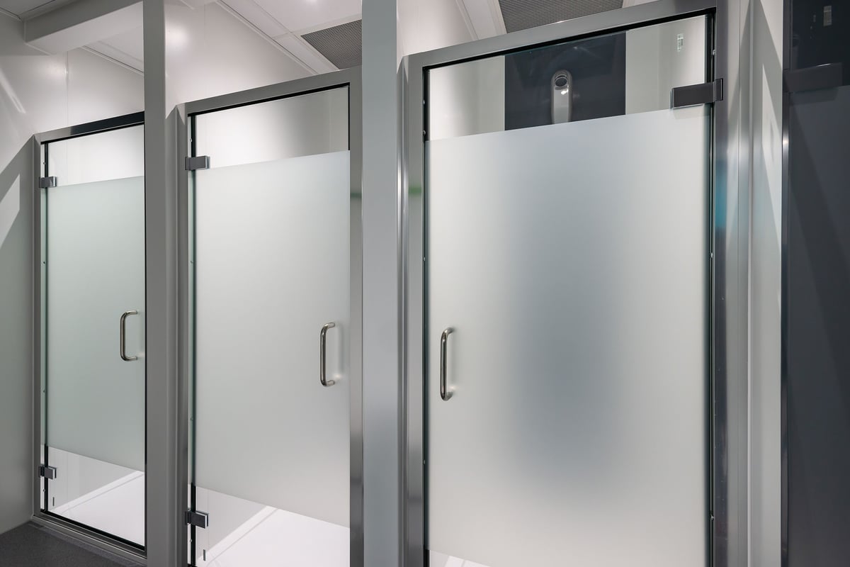 PureGym Stratford-upon-avon: Shower stalls with glass doors and metallic frames.