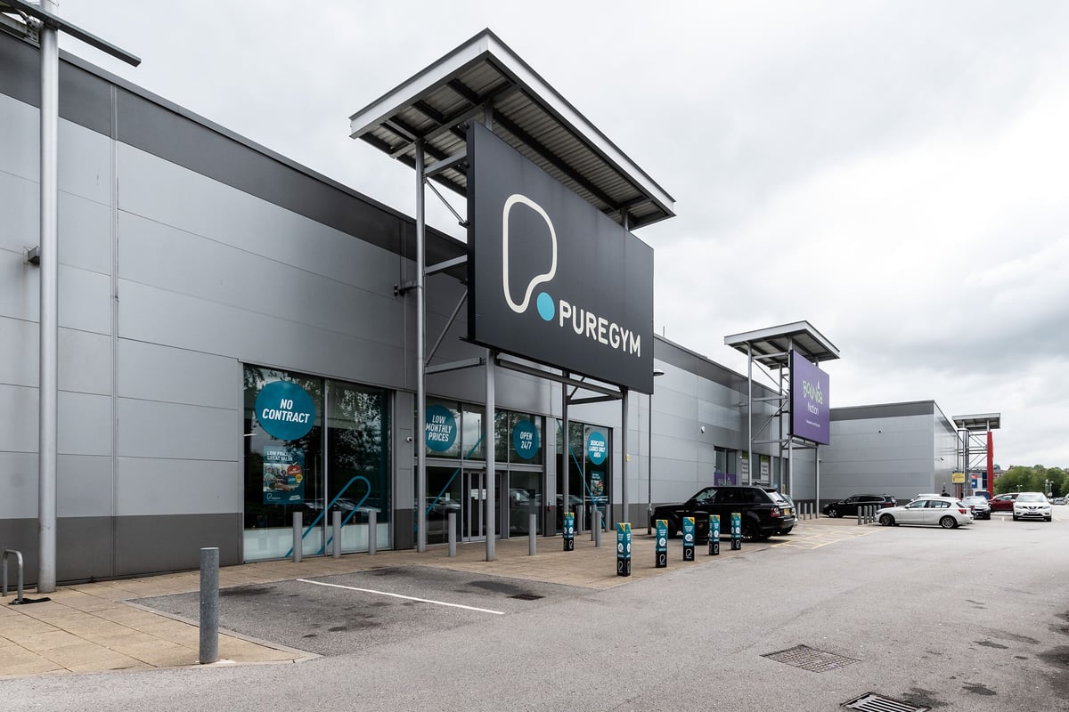 PureGym Oldham: Exterior of a modern gym building with signage and parking spaces.