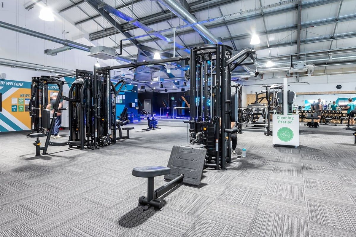 PureGym Stowmarket: Strength training area with squat racks, benches, free weights, and rubberized flooring.
