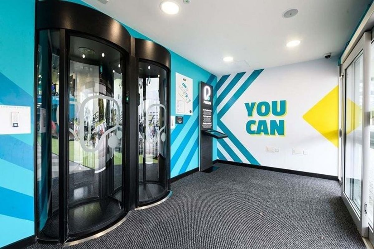 Modern entrance with two black revolving doors and a wall sign saying YOU CAN