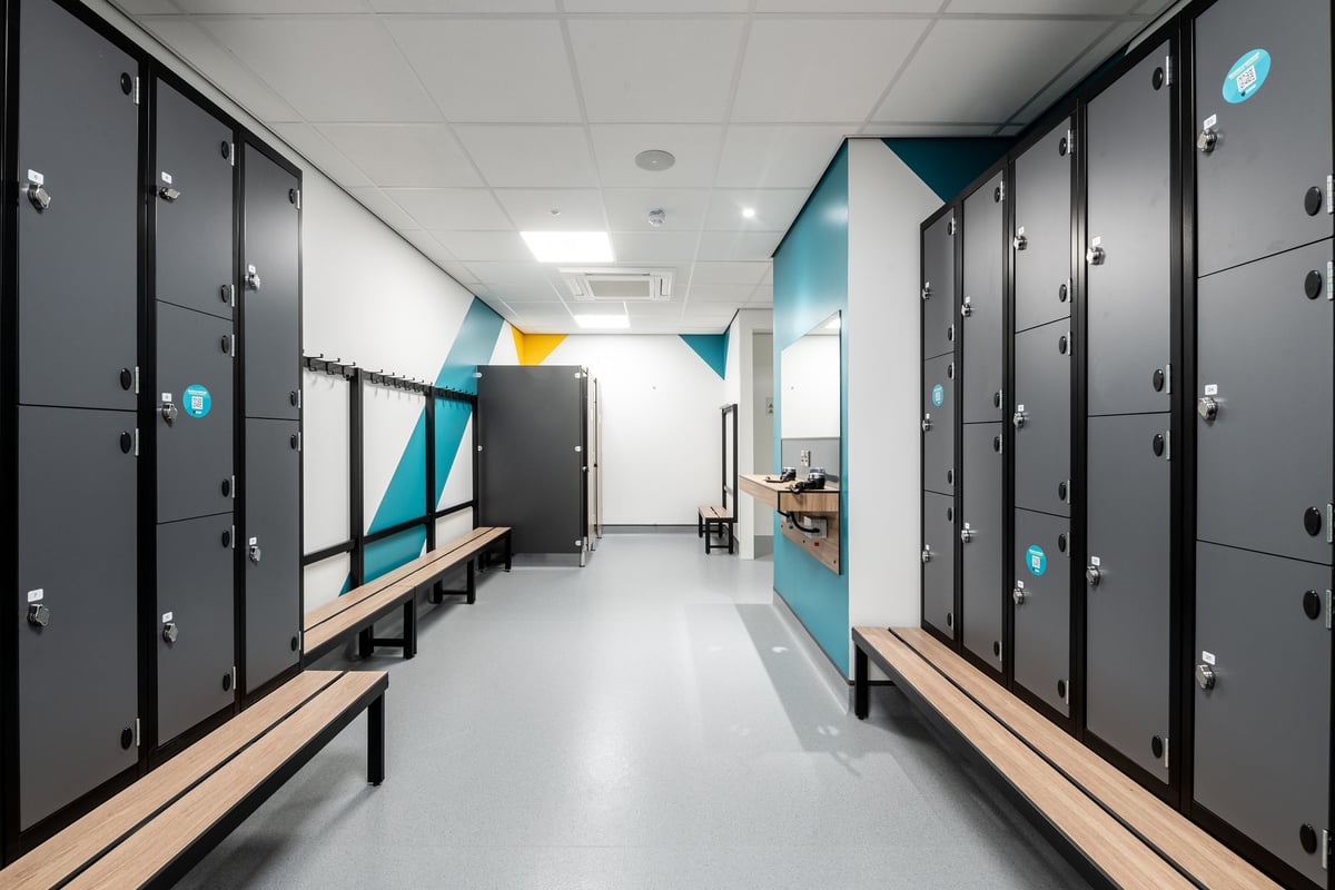 PureGym Derby Kingsway Retail Park: Rows of lockers, benches, and tiled flooring in a changing room setting.
