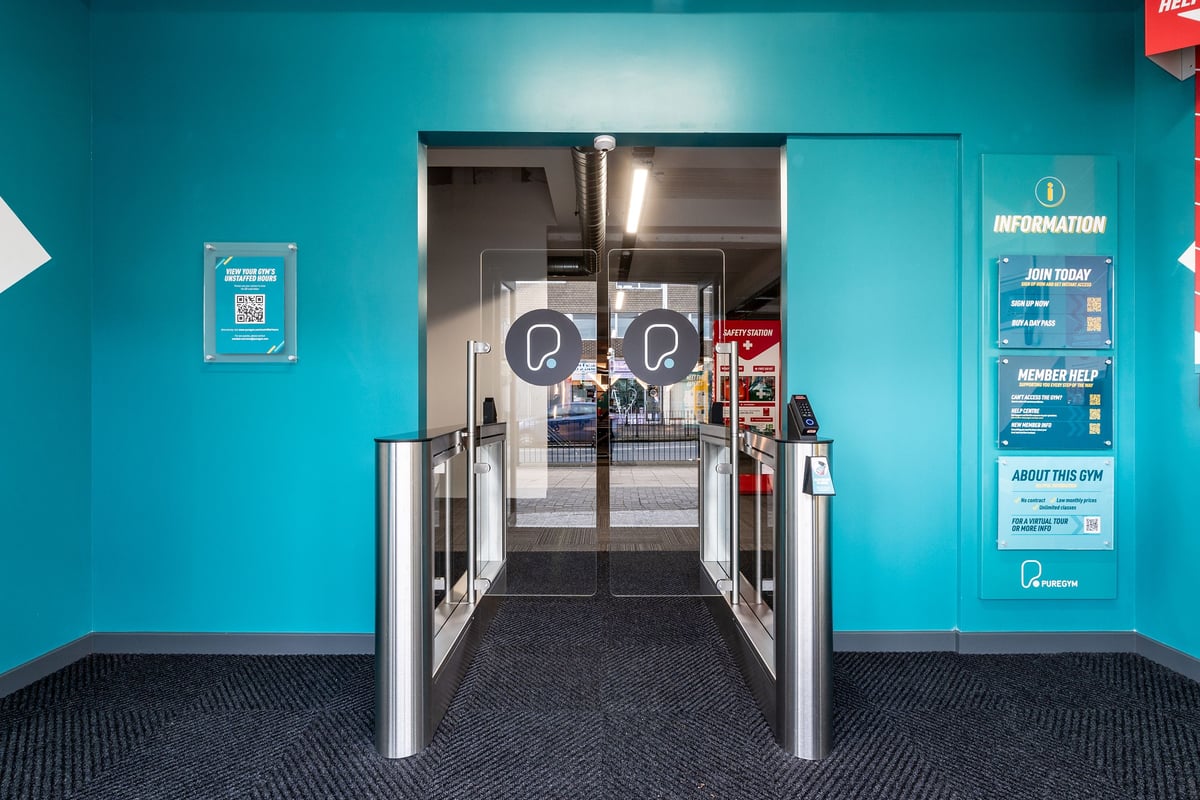 PureGym London Hornchurch: Entrance area with turnstiles, information kiosks, and tiled floors.