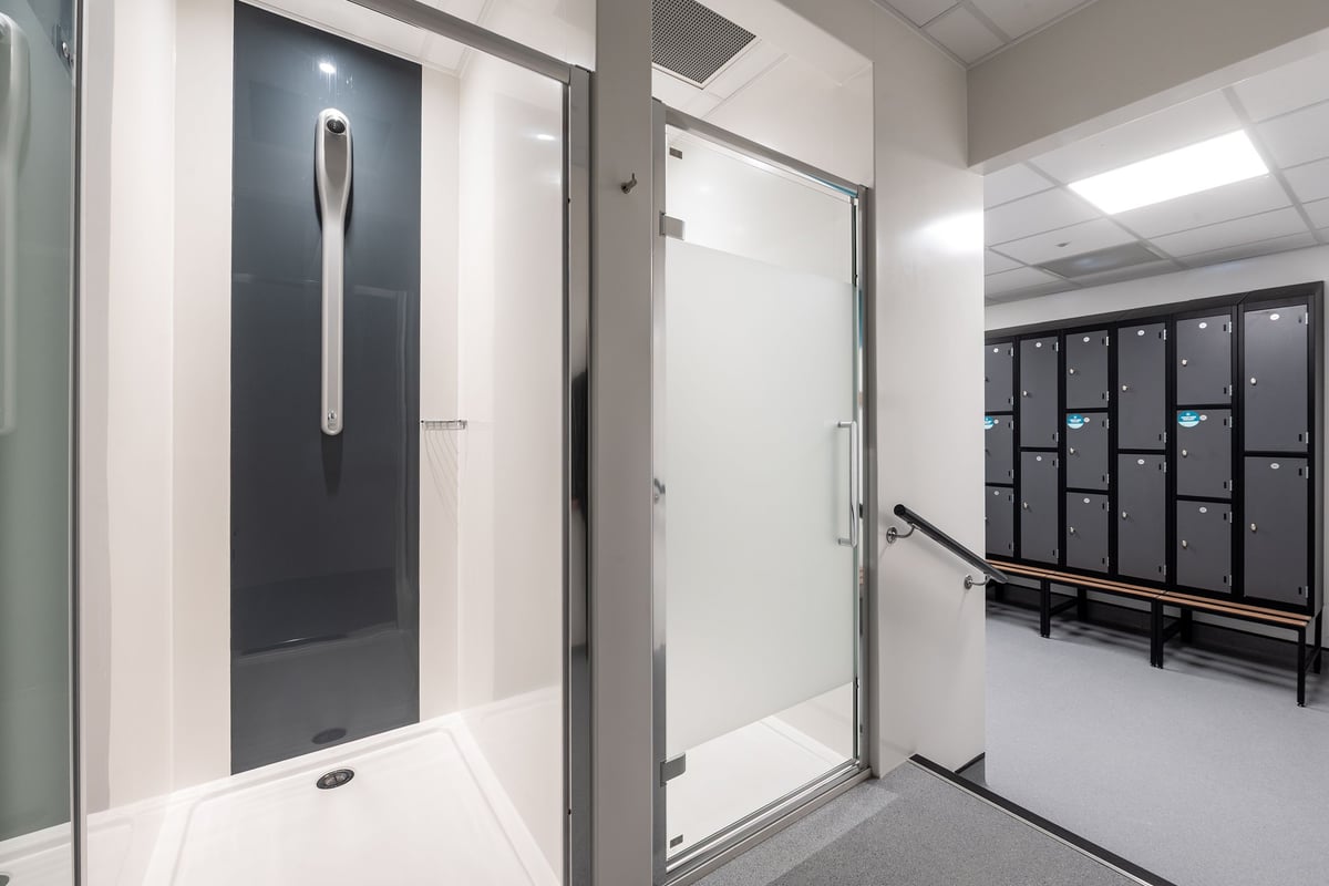 PureGym Bridgend: Changing rooms with lockers, benches, private cubicles, and shower areas.