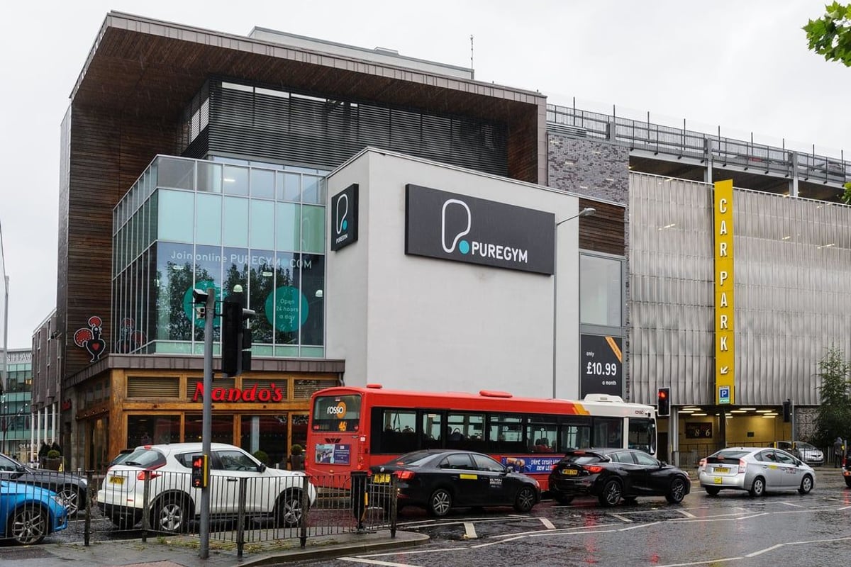 PureGym Bury: Modern gym building exterior with signage and red double-decker bus on street.