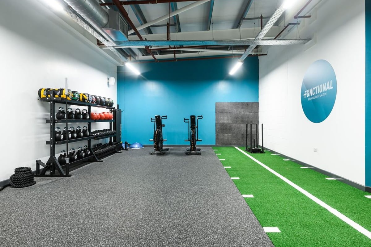 PureGym Cambridge Grafton Centre: Functional training area, weight racks, turf, exercise equipment, mirrored wall.