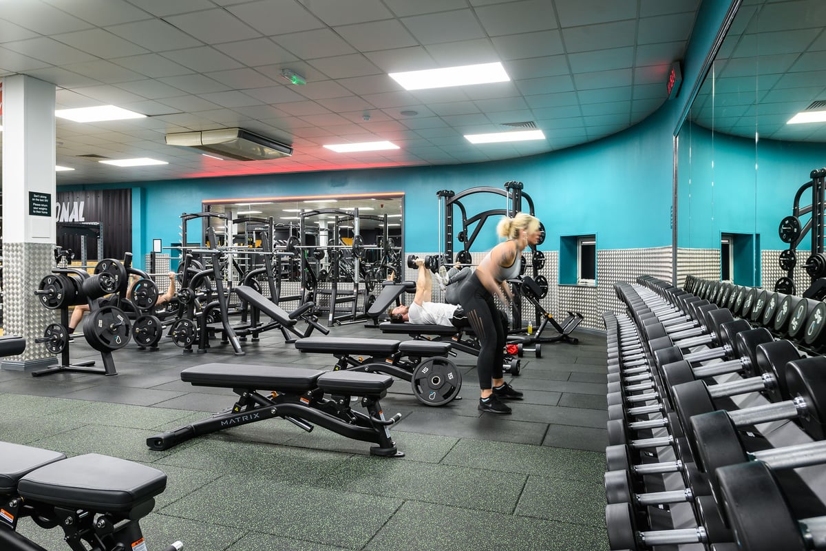 PureGym Waterlooville: Strength training area with weight machines, free weights, benches, and mirrors.
