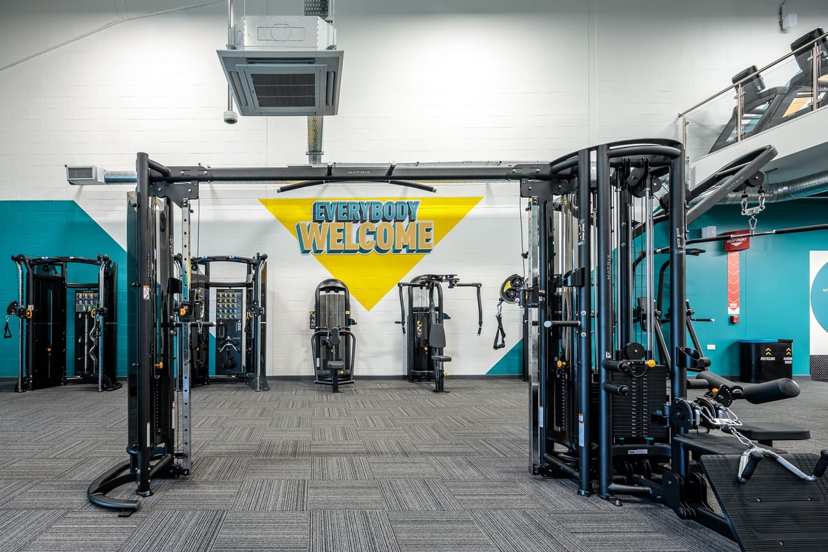 PureGym Frome: Rows of cable machines, weight stacks, benches, and rubberized flooring in a functional training area.