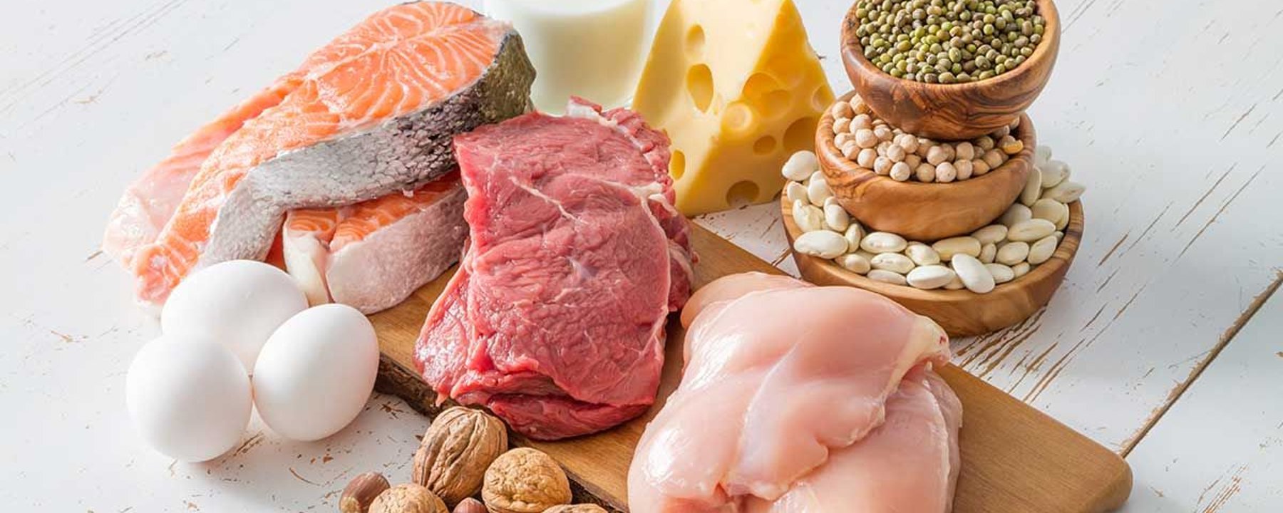 Saumon, bœuf cru, blancs de poulet, œufs, fromage, lait, noix et divers haricots sur une p