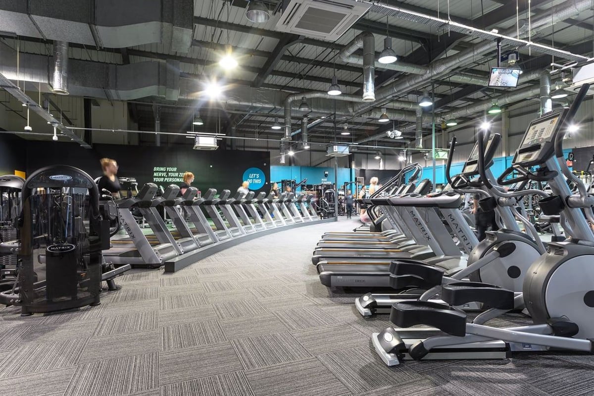 PureGym Bromborough: Rows of treadmills, ellipticals, exercise bikes, and other cardio equipment in a large gym space.