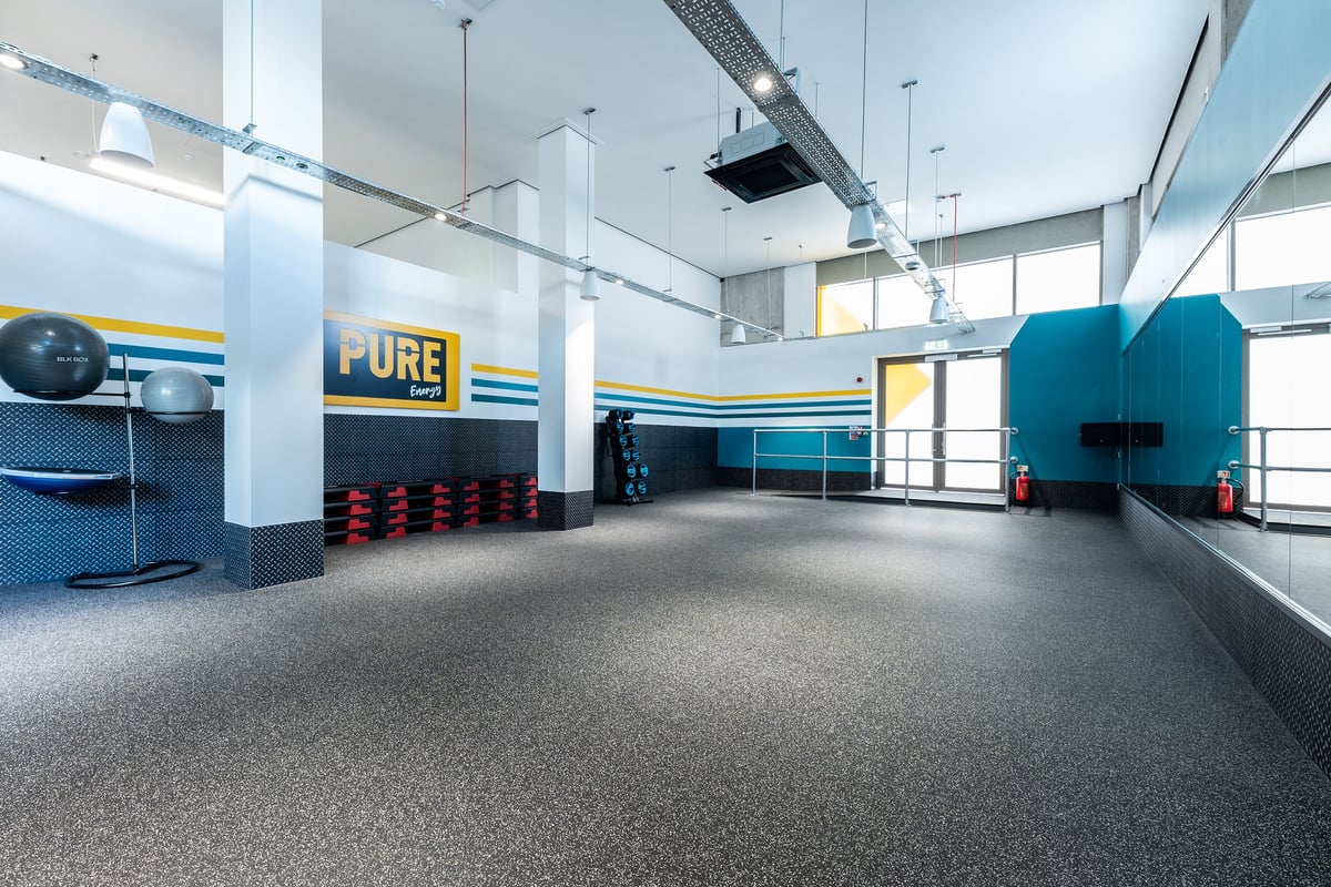 PureGym London Seven Sisters: Resistance machines, free weights, rubberized flooring in a teal and yellow colour scheme.