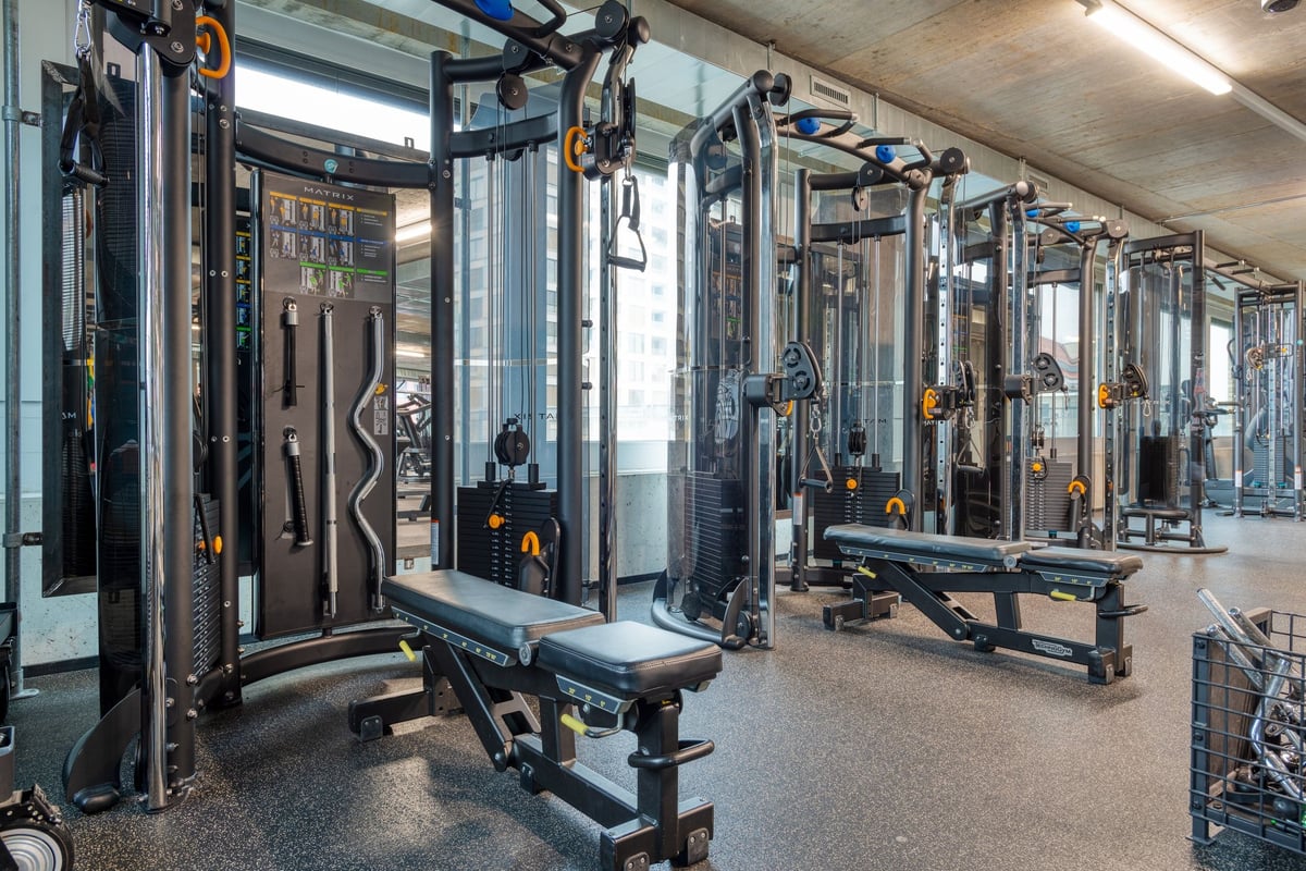 PureGym Lenzburg : une zone de musculation avec des appareils de résistance et des bancs de musculation.