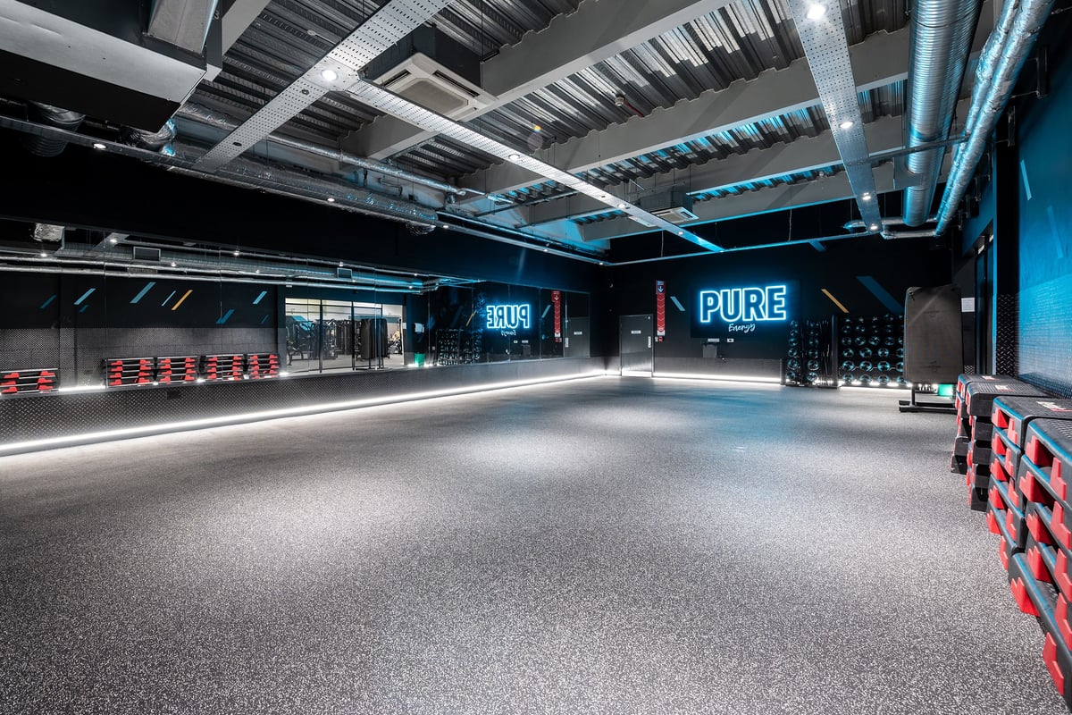 PureGym York: Gym entrance area with blue lighting, Pure signage, and rubberized flooring.