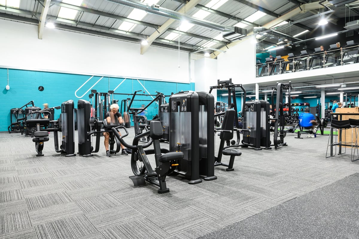 PureGym Burgess Hill: Weight machines, resistance equipment, free weights, benches on rubberized flooring in spacious gym.