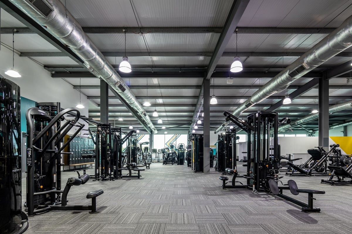 PureGym Cardiff Gate: Rows of weight machines, benches, free weights, and rubberized flooring in a gym setting.