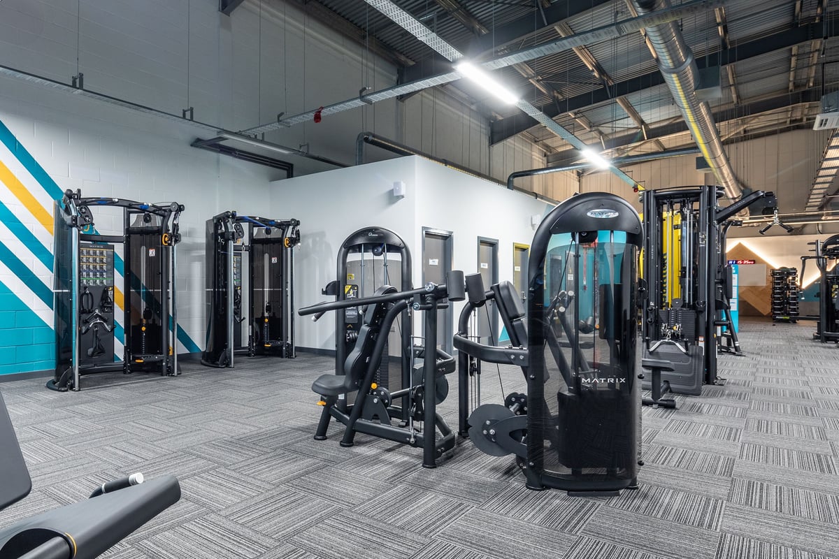 PureGym Wantage: Rows of weight machines, resistance equipment, benches, and rubberized flooring in a gym interior.