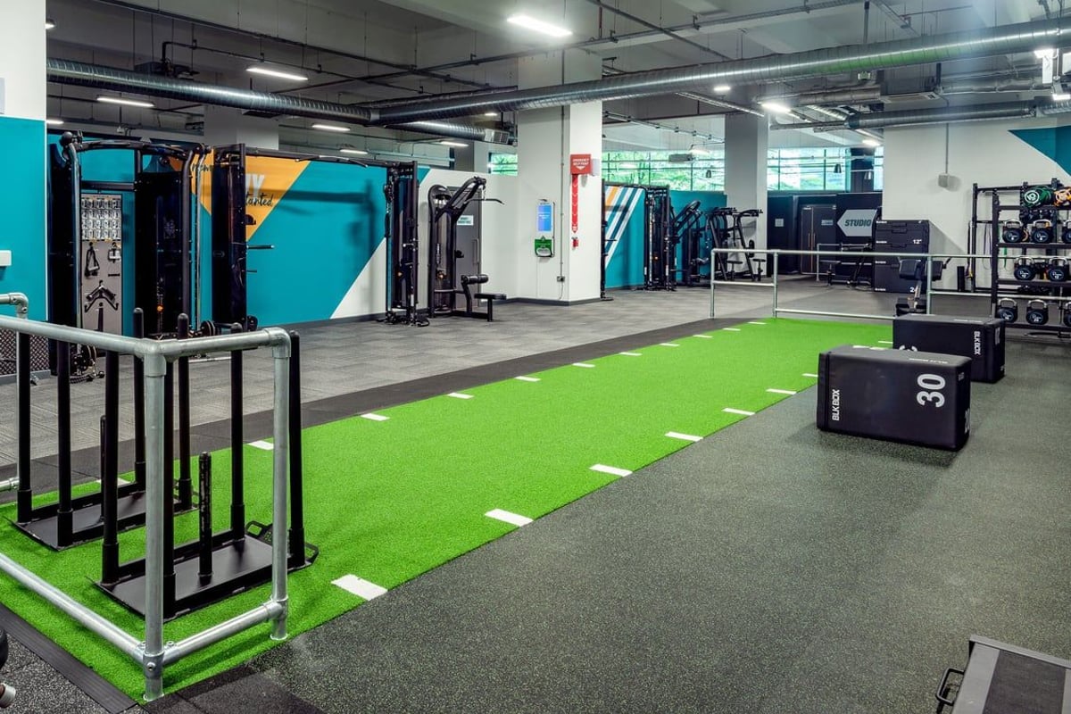 PureGym Leicester St Georges Way: Gym with green turf area, racks, weights, fitness machines, and exposed ductwork overhead.