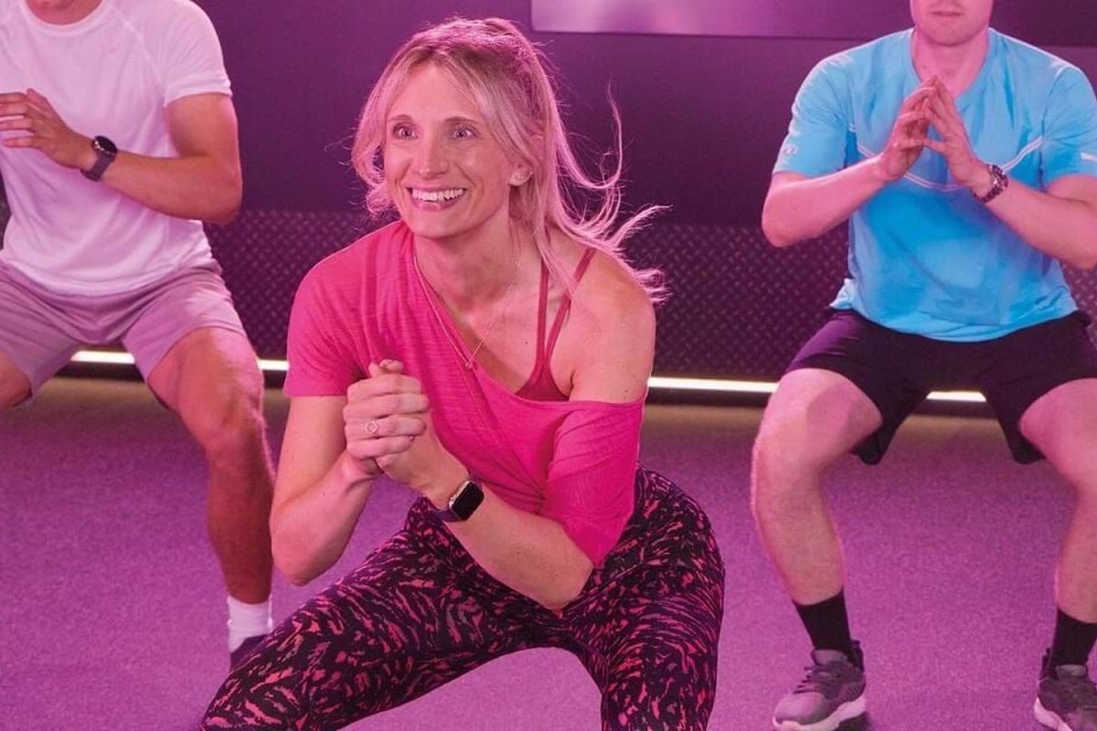 Three people doing squats in a gym with purple lighting