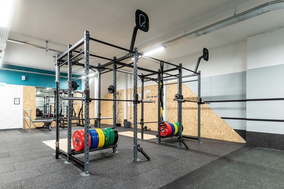PureGym Ormskirk: Metal rig system, weight plates, rubberized flooring in a gym setup.