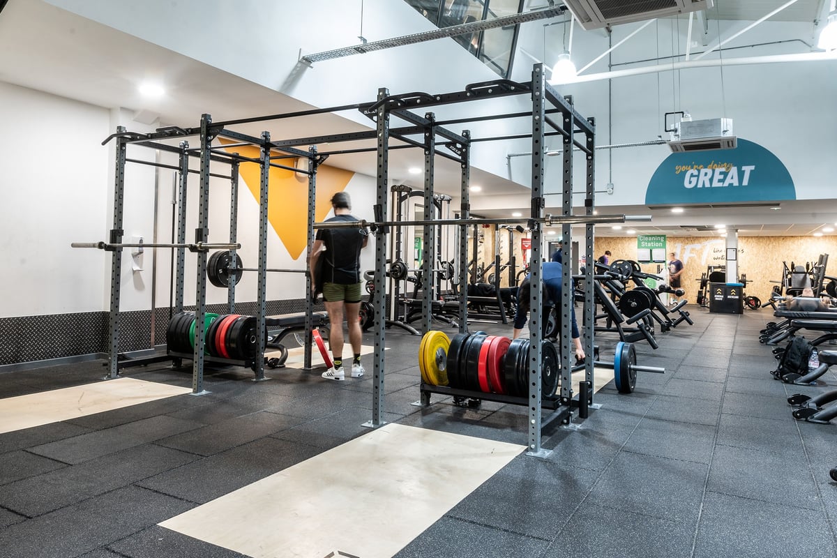 PureGym London Bayswater: Squat racks, weight plates, and rubberized floors in a gym with functional training equipment.