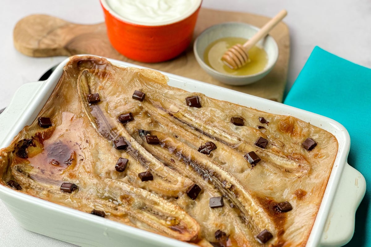 Baked porridge with sliced bananas and chocolate chunks in a white baking dish