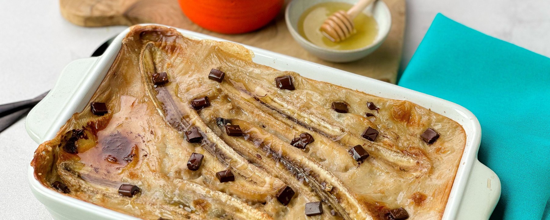Baked porridge with sliced bananas and chocolate chunks in a white baking dish