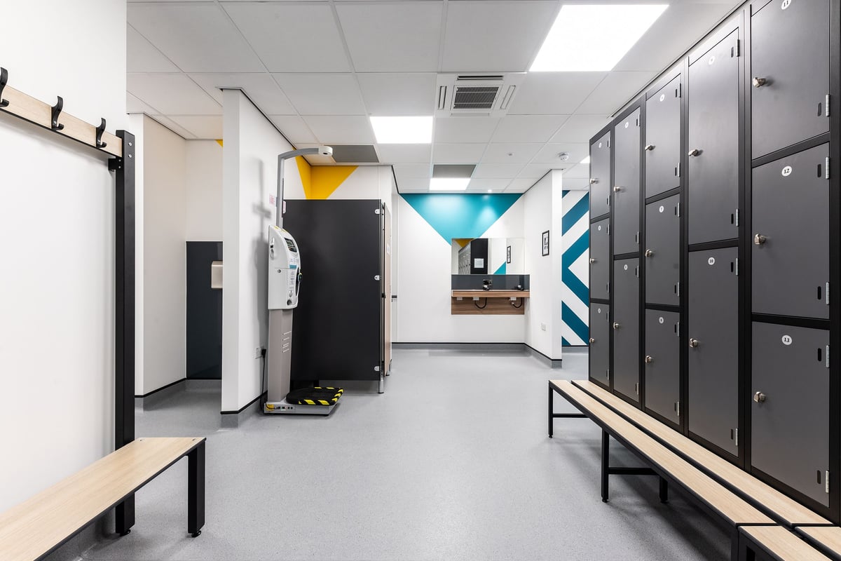 PureGym Selby: Rows of lockers, benches, and an open fridge in a utilitarian changing room.