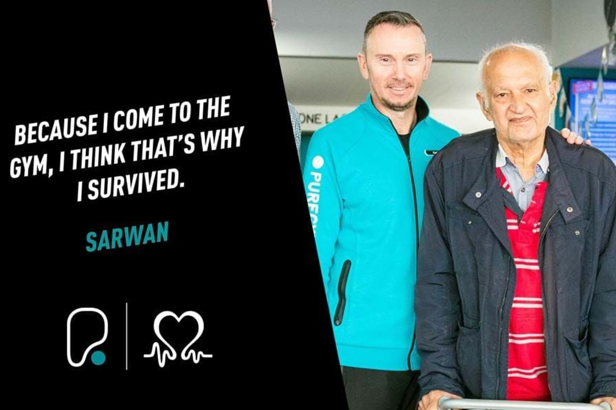 Two men standing side by side, one in a turquoise jacket and the other using a walker.