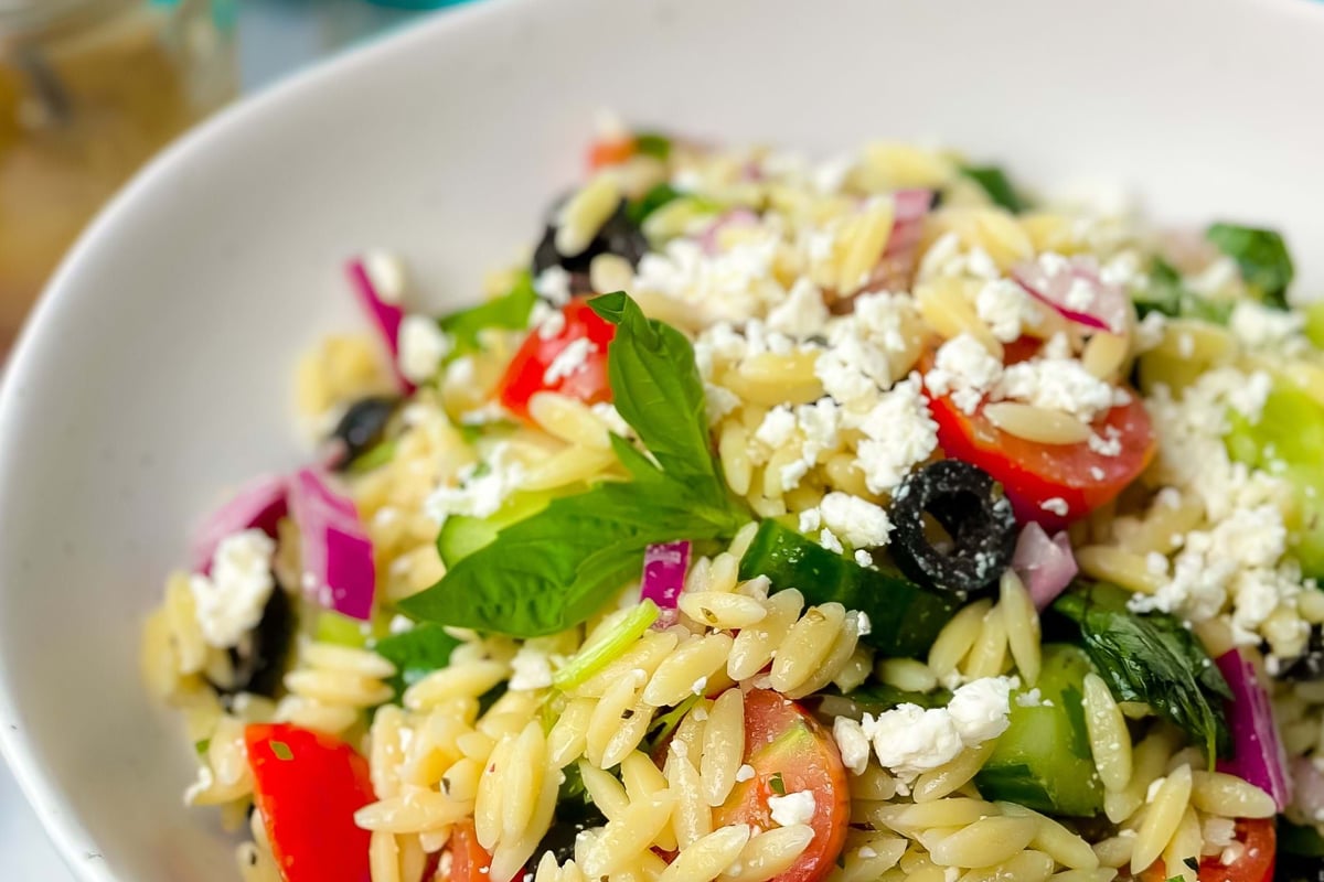 Orzo pasta salad with cherry tomatoes, black olives, cucumber, red onion, feta, and basil
