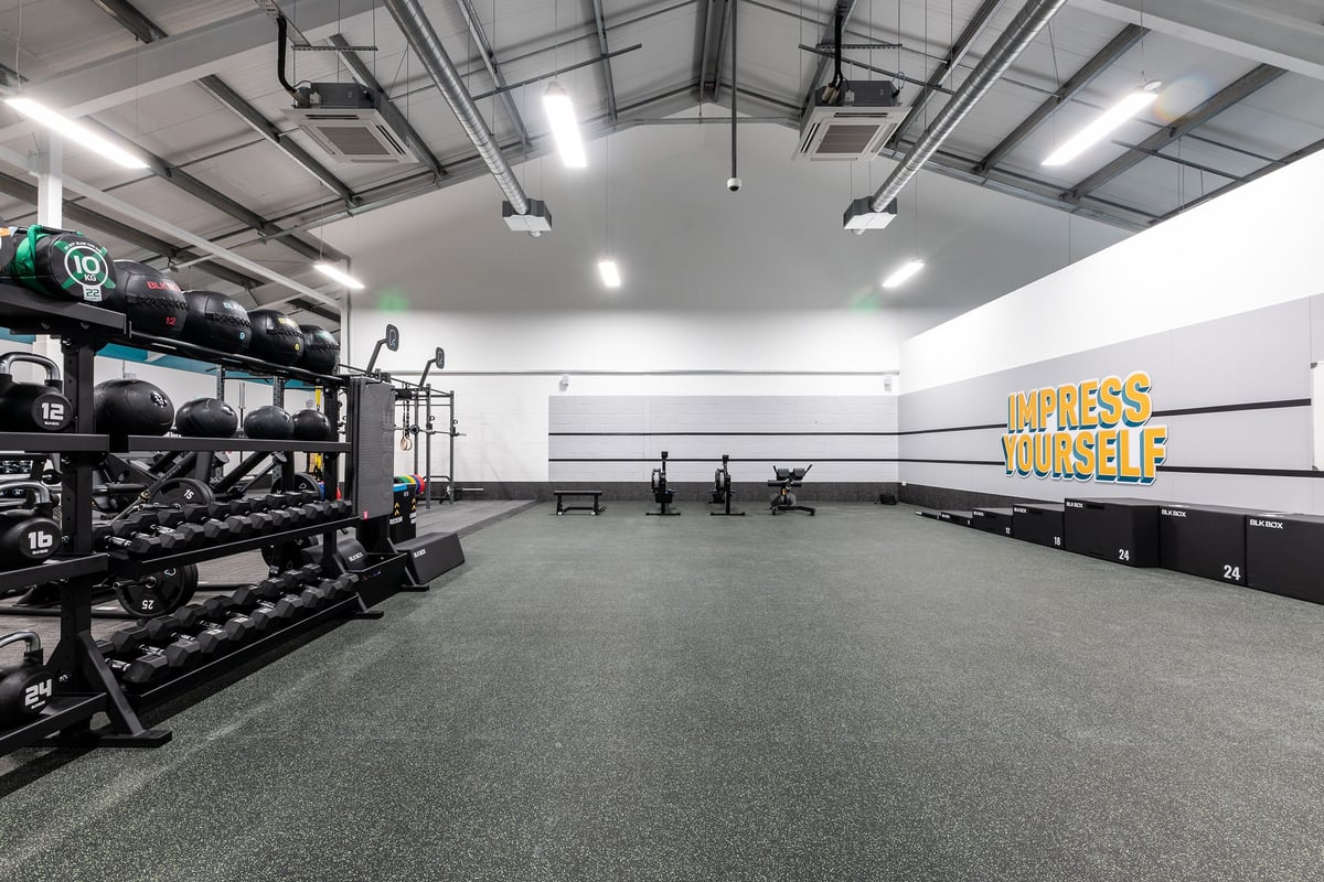 PureGym Uttoxeter: Weights racks, benches, rubberised flooring, mirrors, and strength training equipment in a spacious gym.