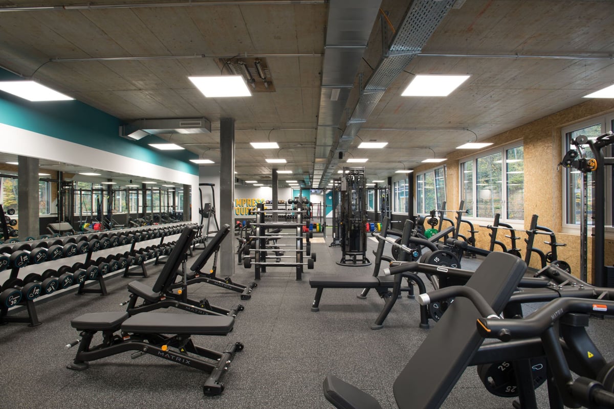 PureGym Adliswil: Des rangées de bancs de musculation, d'haltères, d'étagères à squat et de sols caoutchoutés.