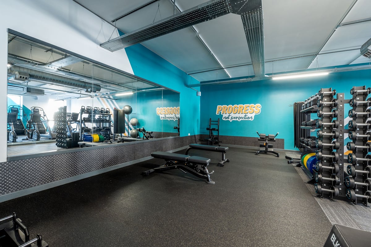 PureGym Stevenage: Weight benches, resistance machines, free weights, and mirrors in a teal and grey fitness studio.