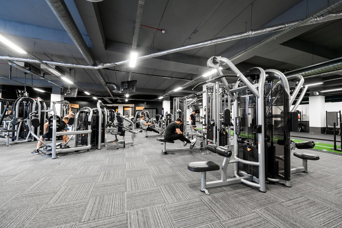 PureGym Bournemouth The Triangle: Resistance machines, benches, weight racks, and rubberized flooring in a dimly lit gym.