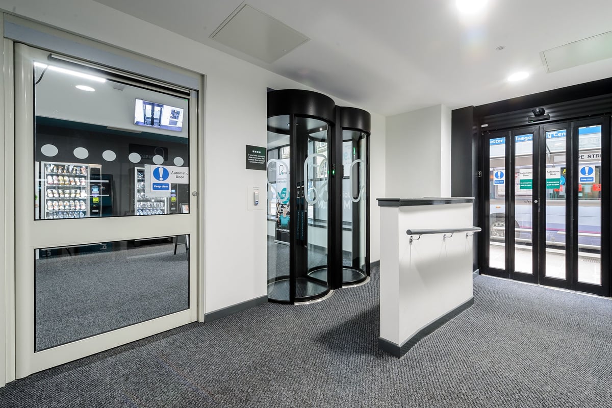 PureGym Glasgow Hope Street: Vending machines, revolving door entrances, and refrigerated beverage displays.