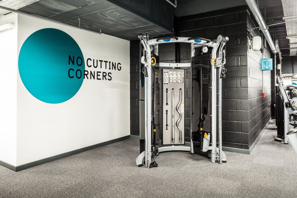 PureGym Altrincham: Resistance training area with robotic exercise machines, mirrors, and motivational wall signage.