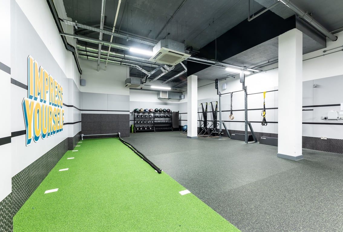 PureGym London Hammersmith Palais: Rubberized green turf, weight racks, free weights, and a strength training rig.