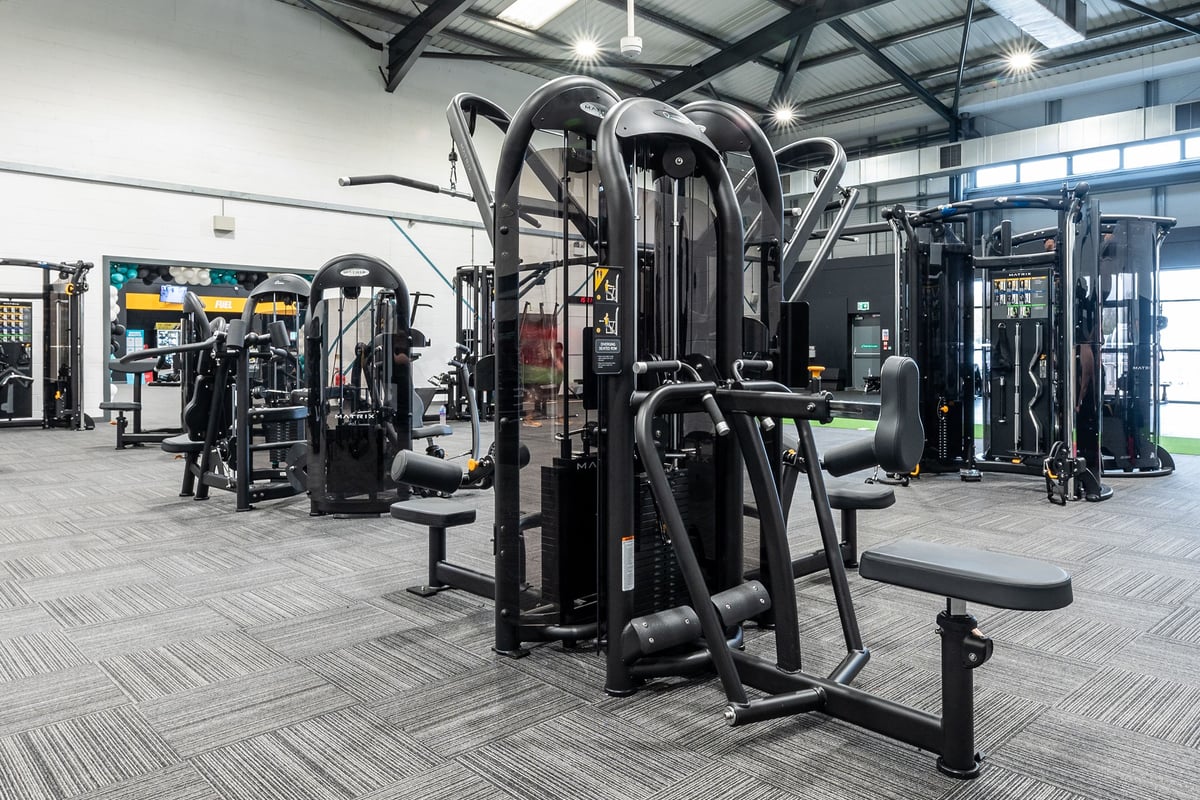 PureGym Leeds Hunslet: Multi-station weight machines, free weights, benches, and rubberized flooring in a gym facility.